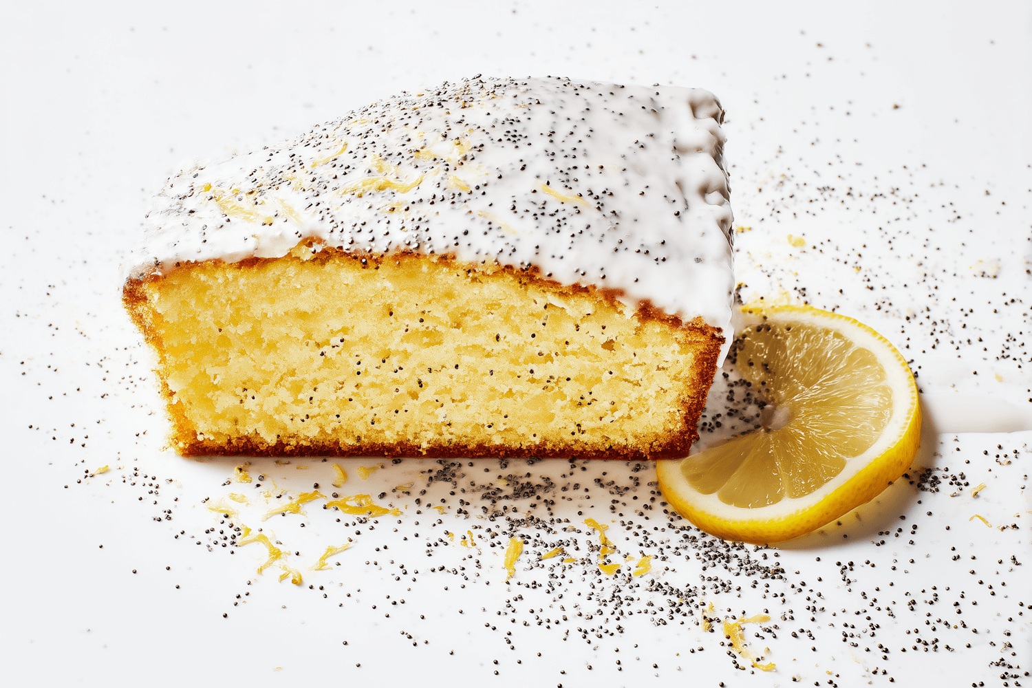 A slice of glazed lemon poppy seed cake with a slice of lemon